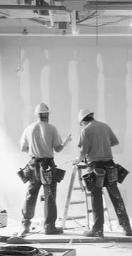 Two people reviewing plans inside a space under construction